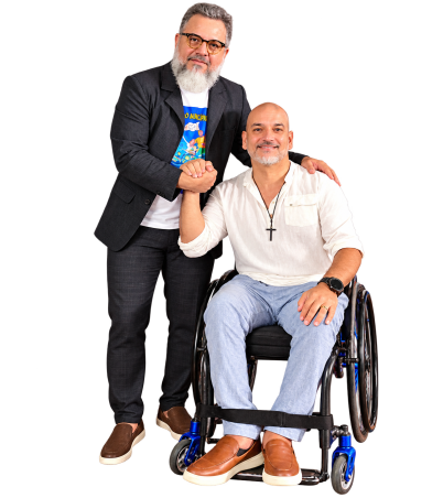 PS CARVALHO e NATANAEL SOUZA juntos de mãos dadas. PS CARVALHO de pé e Natanael Sousa sentado numa cadeira de rodas.